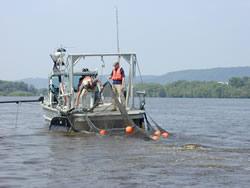 The USGS research vessel, here shown bringing in a trawl net, provides unique capability to sample fishes in the deep channels of large rivers. (photo)